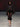 Look 11 desfile Un Romance Bien Latino 2026: blusa translúcida negra con cuello chimenea y mangas globo acampanadas con pantalón capri ceñido semitransparente con plumas en las pantorrillas, sandalias de tiras de tacón y lentes de sol oscuros.