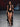 Look 17 desfile Un Romance Bien Latino 2026: top halter negro cruzado al frente con cascada de olanes verticales y abertura central sobre braga negra de tiro alto, zapatillas negras de tacón con pulsera y aretes dorados.